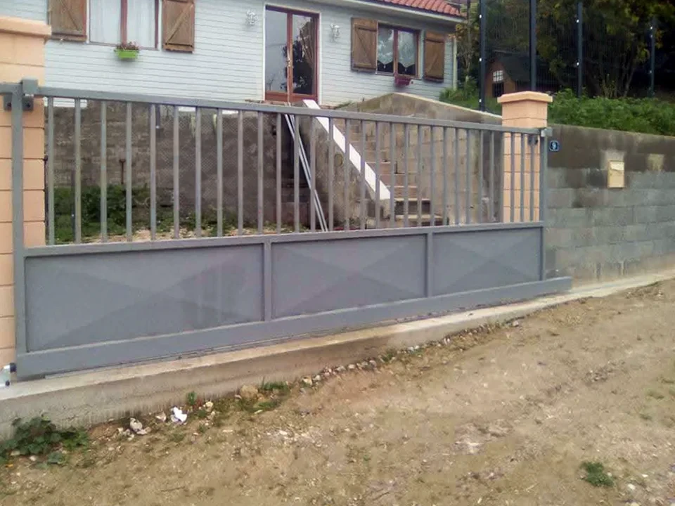 Extérieur résidentiel avec clôture métallique noire s'étendant le long d'une pelouse verte