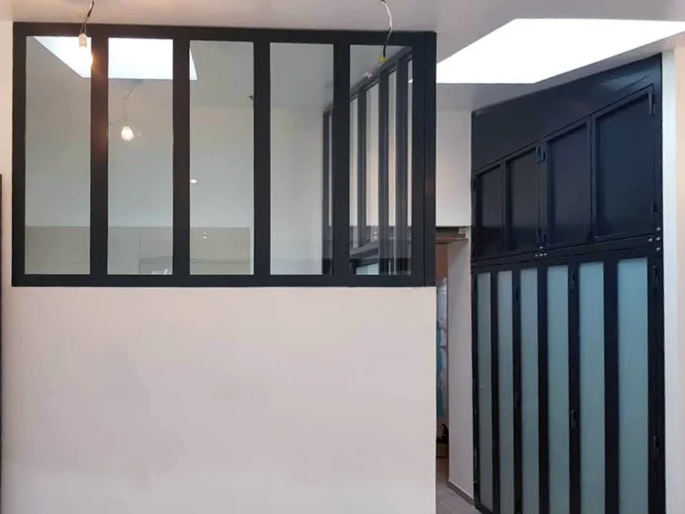 Intérieur moderne avec cuisine ouverte, escalier métallique noir et murs en briques apparentes rouges