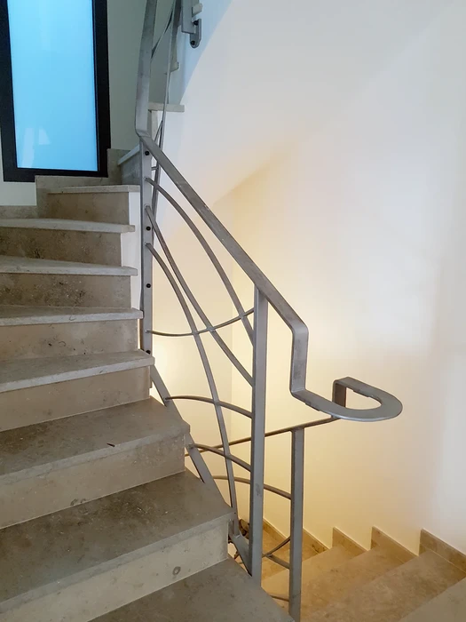 Intérieur moderne avec escalier suspendu à structure métallique noire et marches en bois massif, garde-corps en métal perforé