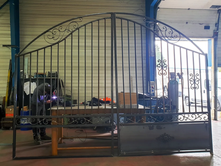 Soudeur professionnel en action dans un atelier industriel, portant un masque de soudage automatique et des gants de protection en cuir jaune