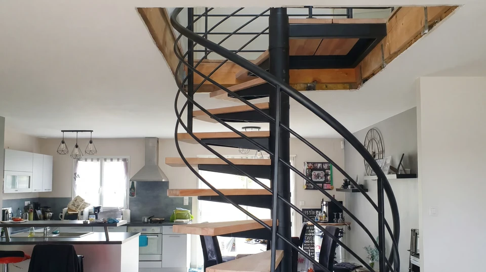 Escalier extérieur métallique avec garde-corps à barreaux horizontaux longeant un mur de briques rouges