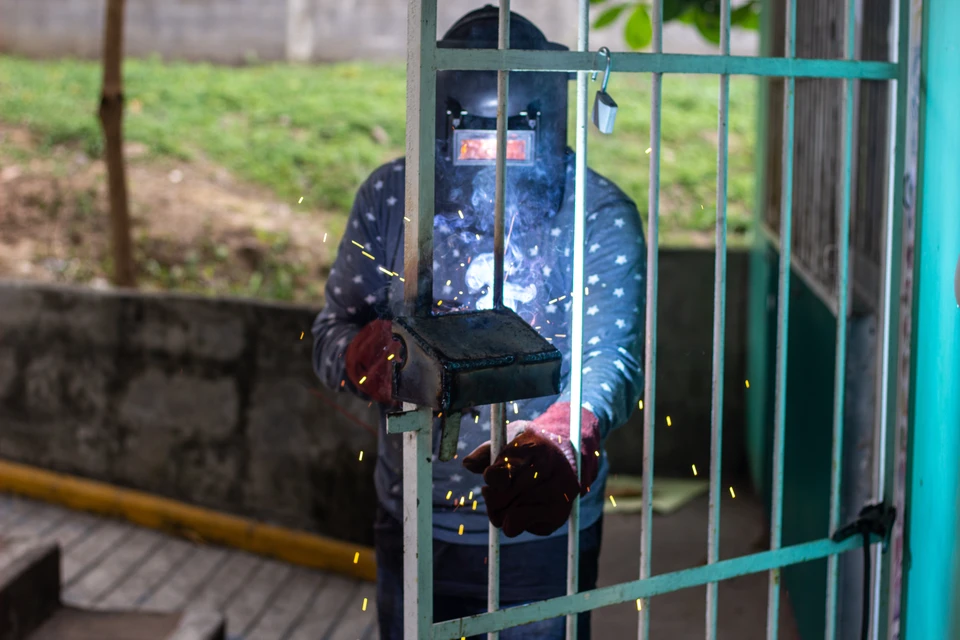 Atelier intérieur, artisan utilisant une meuleuse d'angle sur pièce métallique, étincelles oranges vives, mains expertes en action, travail de précision